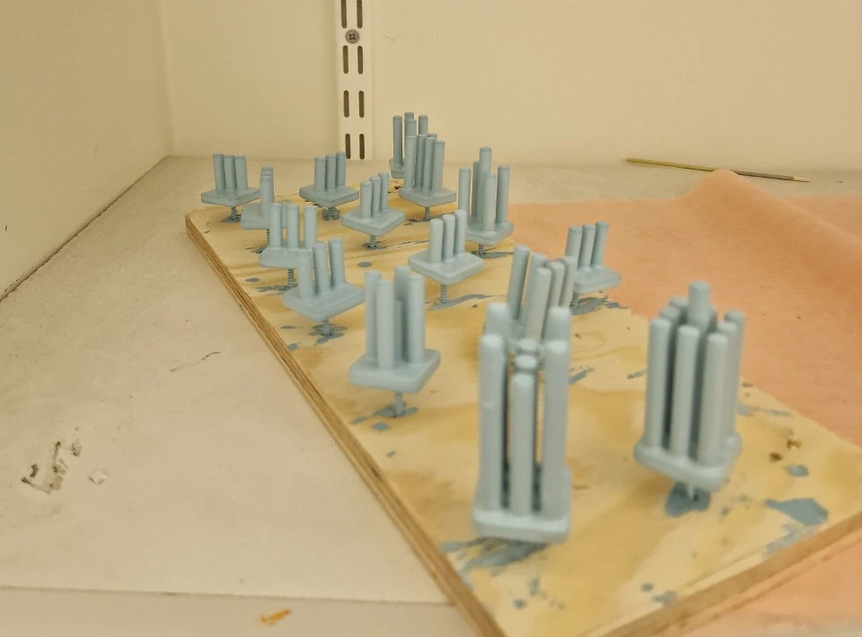Blue painted chess-piece prototypes on a board during development