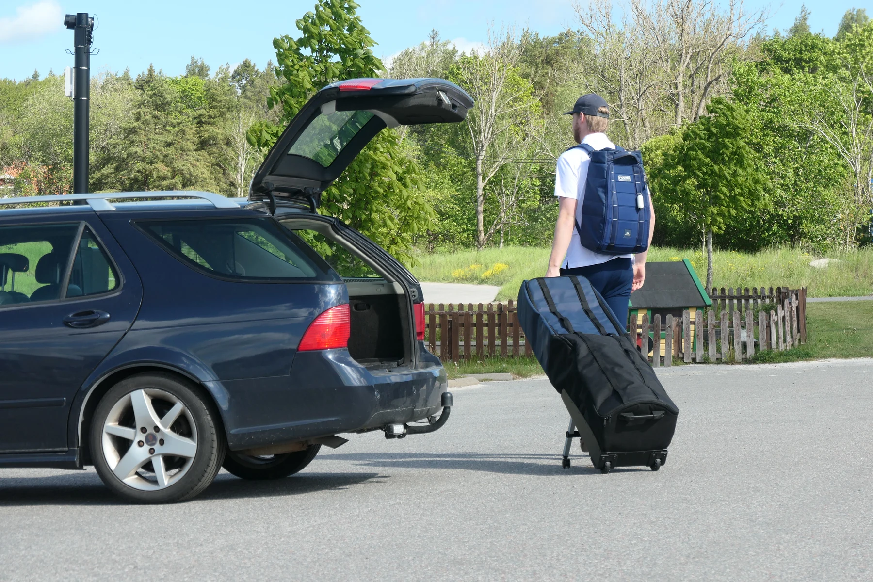 Person moving the completed golf travel-bag prototype beside an open car boot
