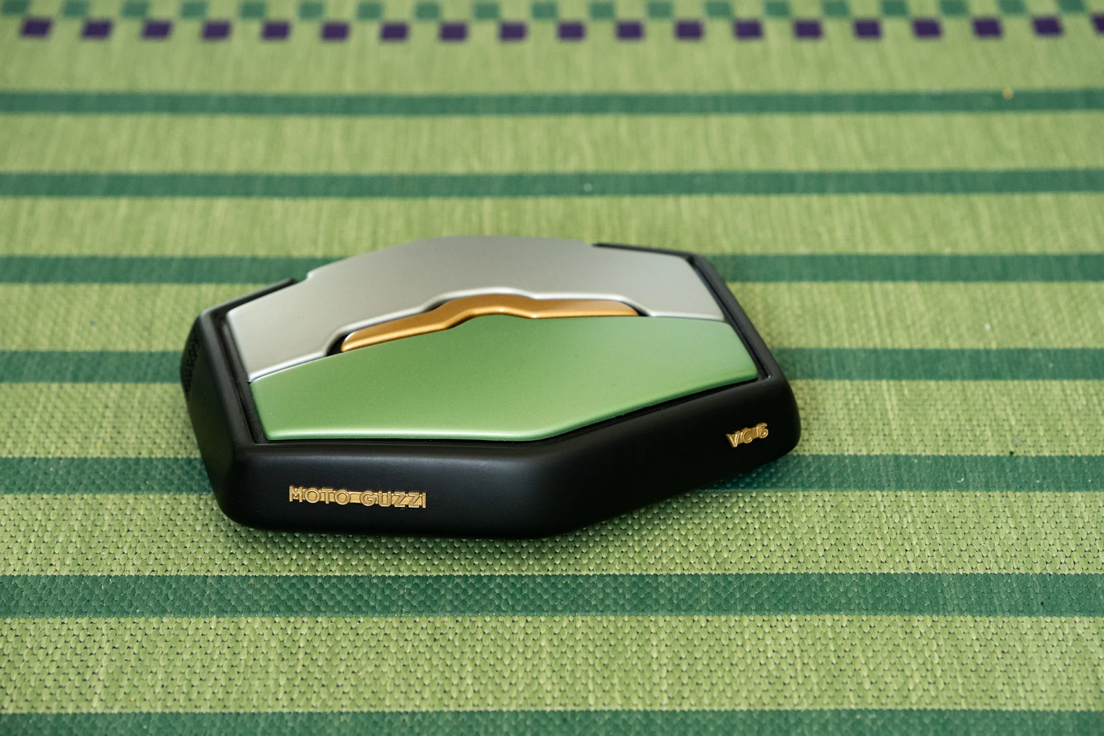 Finished Moto Guzzi robot vacuum with green, silver and gold panels on a striped green rug